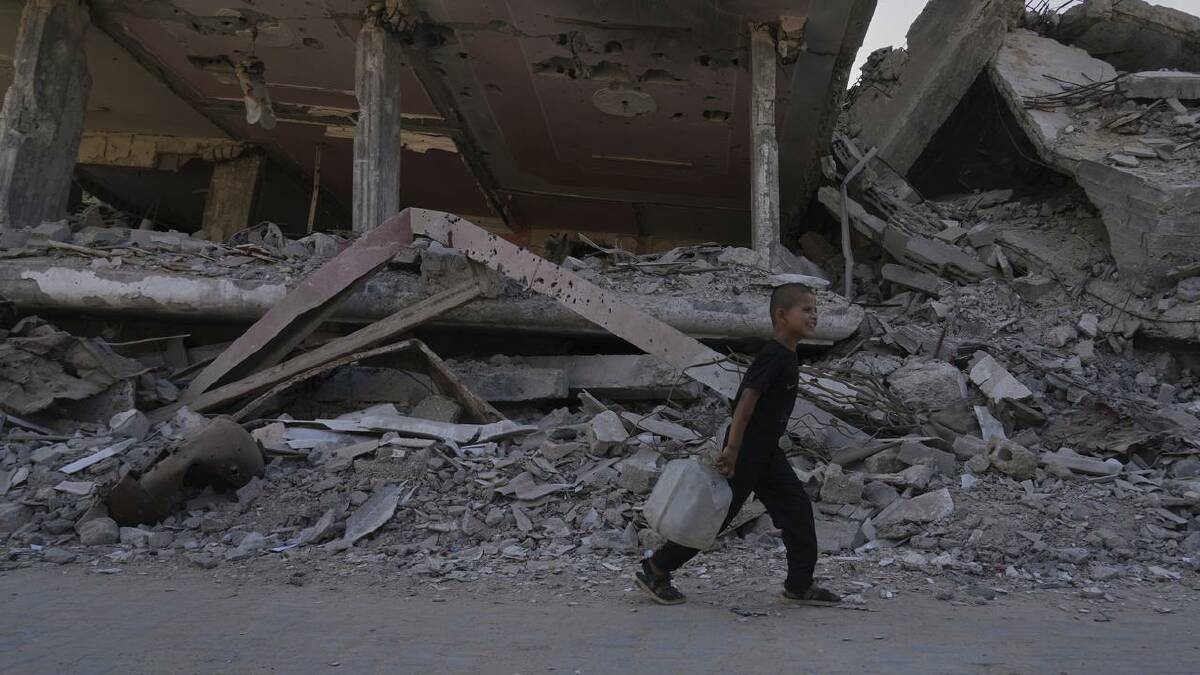 A Palestinian boy walks past buildings destroyed during Israeli air and ground operations. (AP PHOTO)