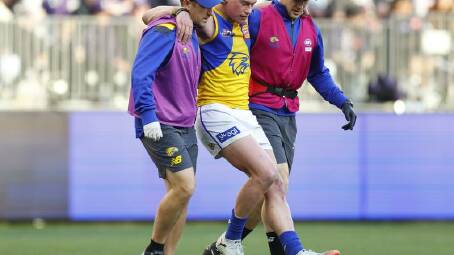 Harley Reid is helped off the ground after suffering an ankle injury in the loss to the Dockers.
 Photo: James Worsfold/AAP PHOTOS