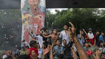 Protesters celebrate beside a defaced portrait of ousted Bangladesh prime minister Sheikh Hasina. Photo: AP PHOTO