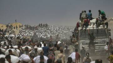 Gaza residents carry bags of flour after lorries with food aid were allowed into the enclave. Photo: EPA PHOTO